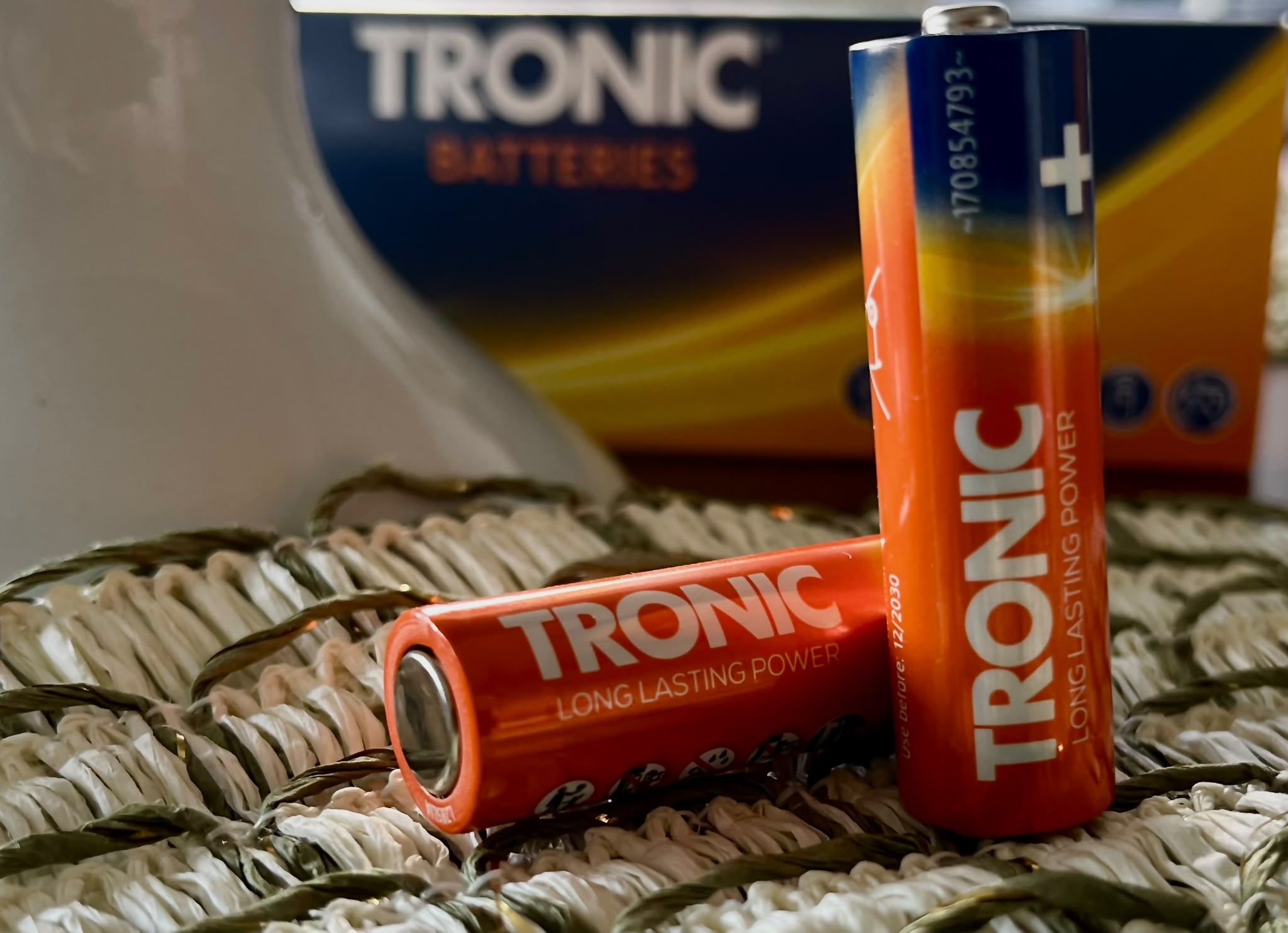 Baterie Tronic na plecionej powierzchni, z opakowaniem w tle